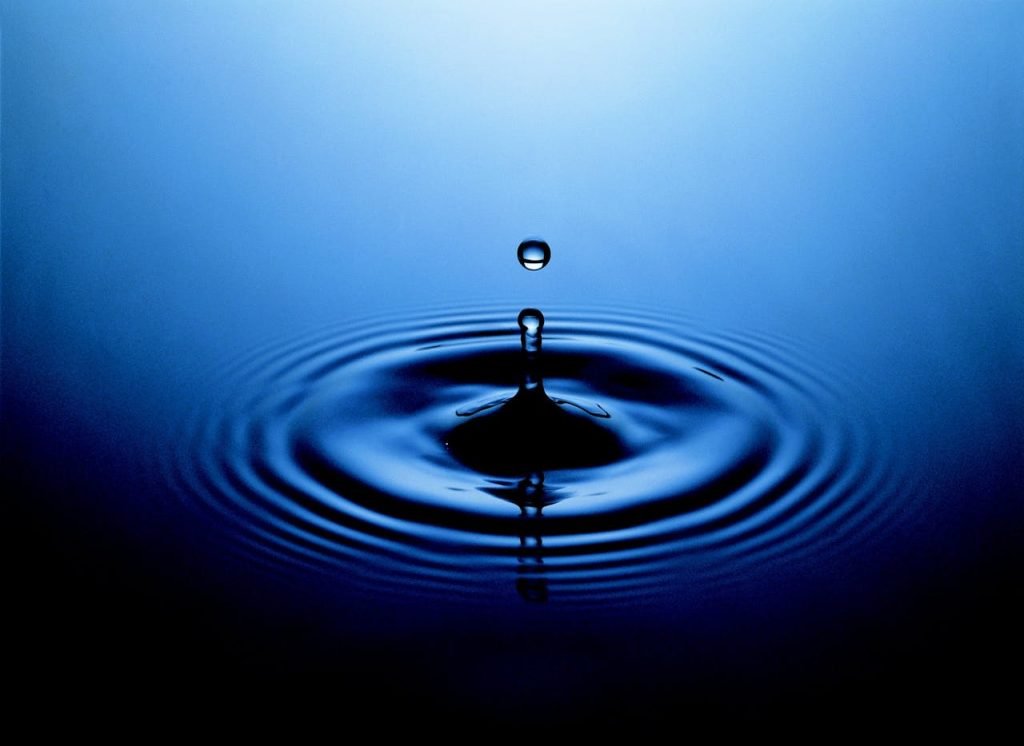 Stunning close-up of a water drop creating ripples on a serene blue surface.